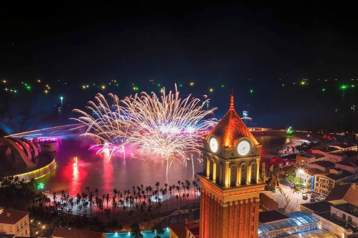 Ein historischer Glockenturm mit angrenzendem Wasserspiel und Feuerwerk.