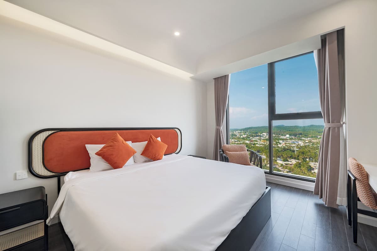 A hotel room with a large bed, a view of a cityscape, and a modern design.