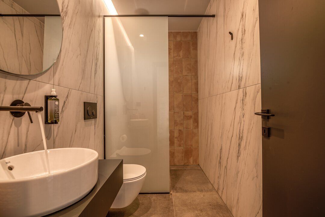 Une salle de bain moderne avec un lavabo, des toilettes et une douche en marbre.