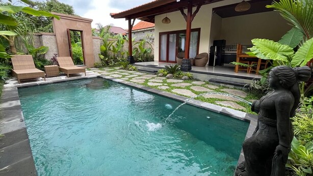 Ein Schwimmbecken mit Liegestühlen, einer Statue und einer überdachten Terrasse.