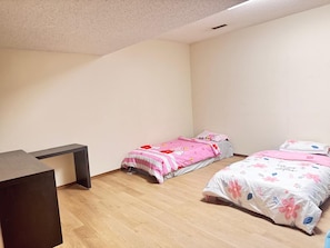 A bedroom with two beds, a desk, and a slanted ceiling. - Sandstone Homestay (Calgary)