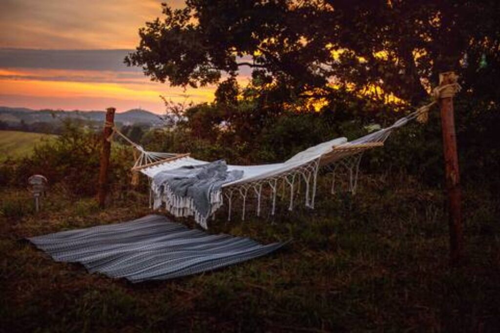 Un hamac installé dans un cadre naturel, avec une couverture posée sur le sol.