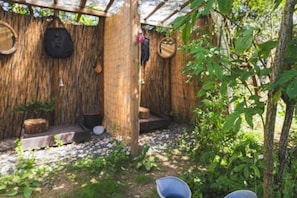 A rustic outdoor area with a wooden structure, a thatched roof, and a small seating area.