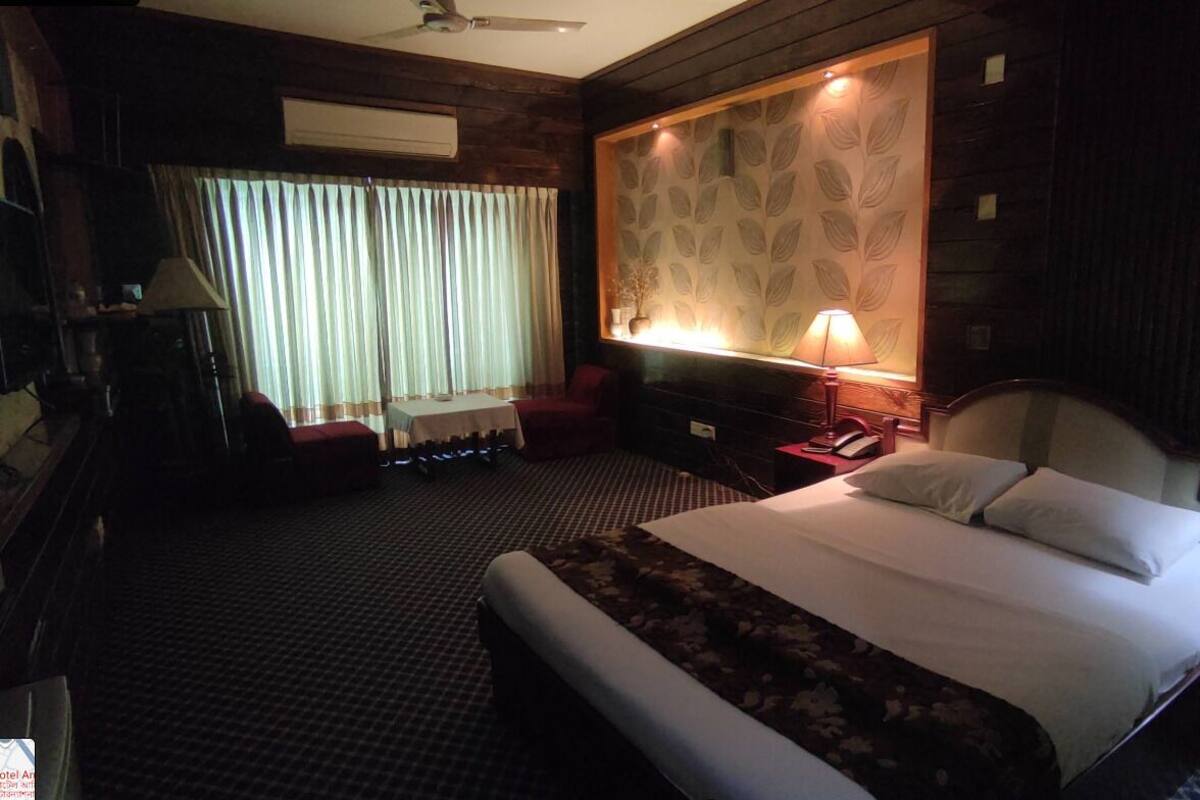 Habitación de hotel con una cama grande, un escritorio, una silla, una lámpara, un teléfono y una ventana con cortinas.