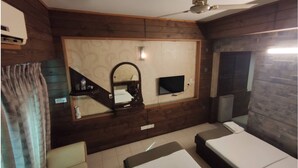 Una habitación con cama, televisión, espejo y ventilador de techo.