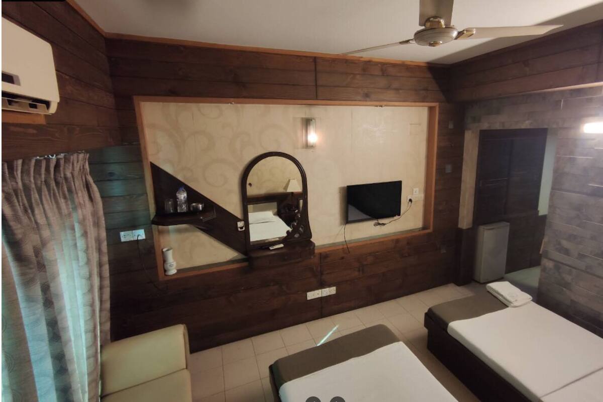 Una habitación con cama, televisión, espejo y ventilador de techo.