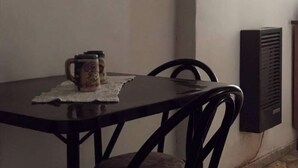 A dining table with a mug and a small container, a chair, and a wall-mounted air conditioning unit.