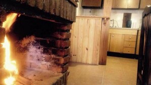 A kitchen with a brick oven, wooden cabinets, and a tiled floor.