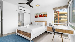 Ein modernes Hotelzimmer mit Bett, Schreibtisch, Stuhl und einem großen Fenster mit Blick auf Gebäude.