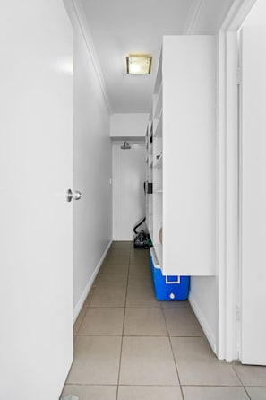 A narrow hallway with white walls, a tiled floor, and a door at the end. - Zen Bayline Villa: bayview - balcony - rooftop (Darwin City)