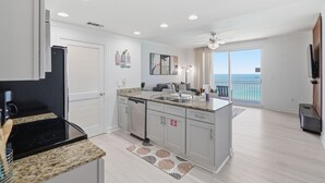 Une cuisine moderne dotée d’un îlot central, d’un coin repas offrant une vue dégagée et d’un balcon avec vue sur la mer.