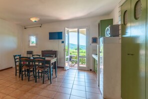 A kitchen with a dining area, a TV, and a view of the outdoors. - LE SOLANE - LE SOLANE BILOCALE (Campo nell'Elba)