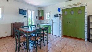 Una cocina con una mesa de comedor, sillas, un refrigerador y un armario verde.