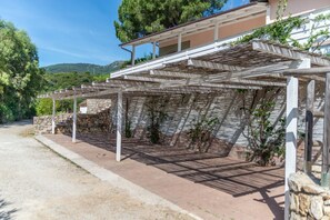 Ein überdachter Außenbereich mit Steinwand und einer Pergola.