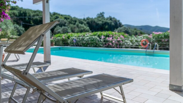 Zona de piscina amb gandules i vista a una piscina.