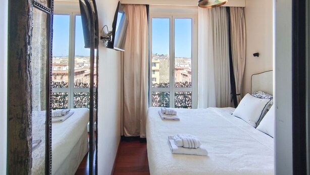 Une chambre d’hôtel avec deux lits, un grand miroir, un ventilateur de plafond et une vue sur le paysage urbain.