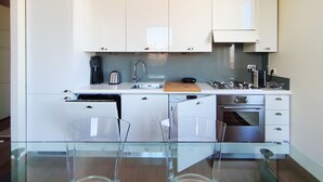 Une cuisine moderne avec des meubles blancs, un lave-vaisselle, une machine à café et une cuisinière.