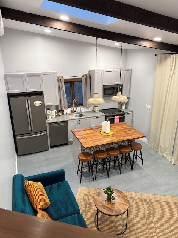 A modern kitchen with a wooden island, bar stools, and a dining table.
