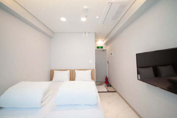 Una habitación de hotel con cama, televisión y un pasillo que conduce a una salida.