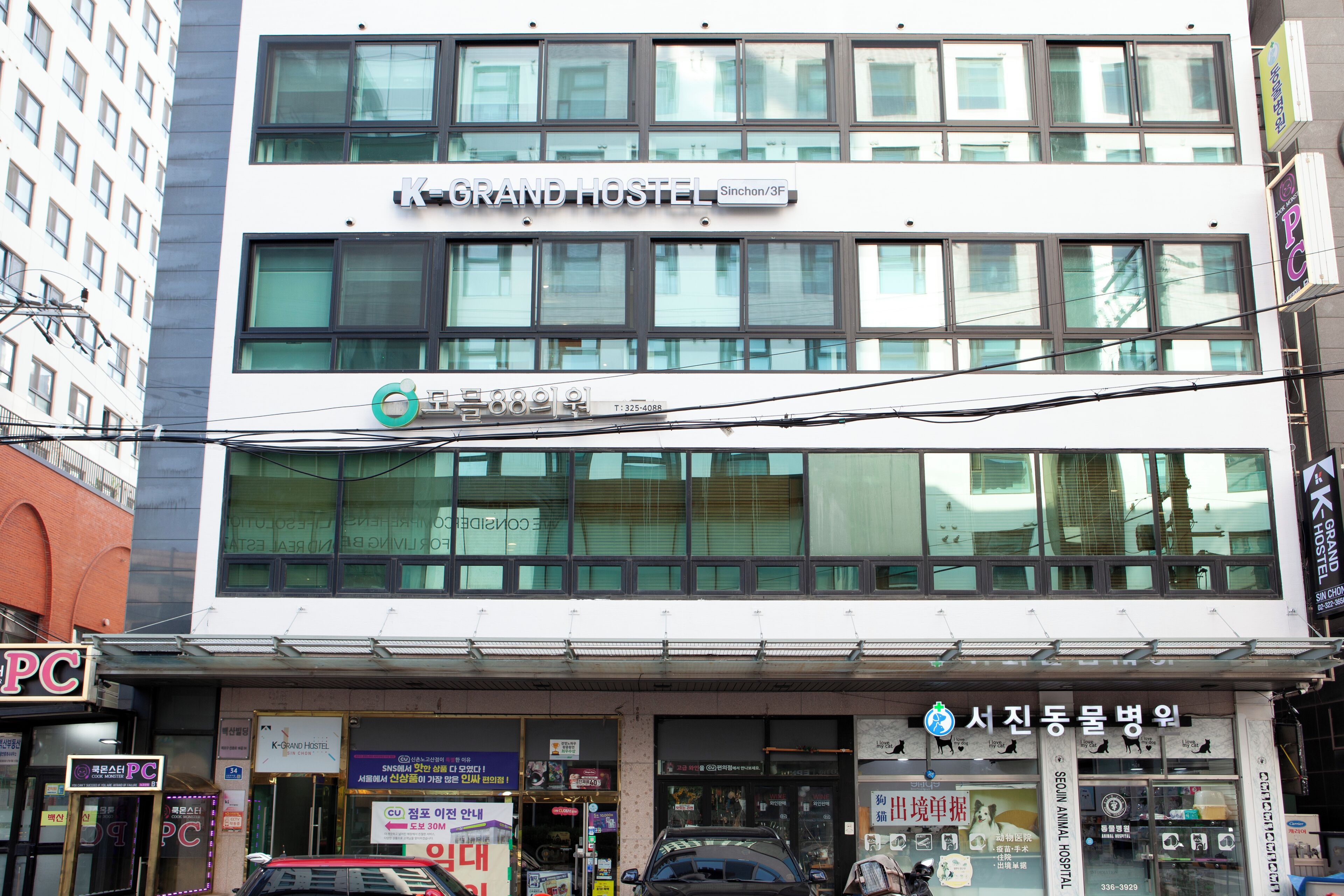 A multi-story building with a sign for 'K-Grand Hostel' and a visible entrance.