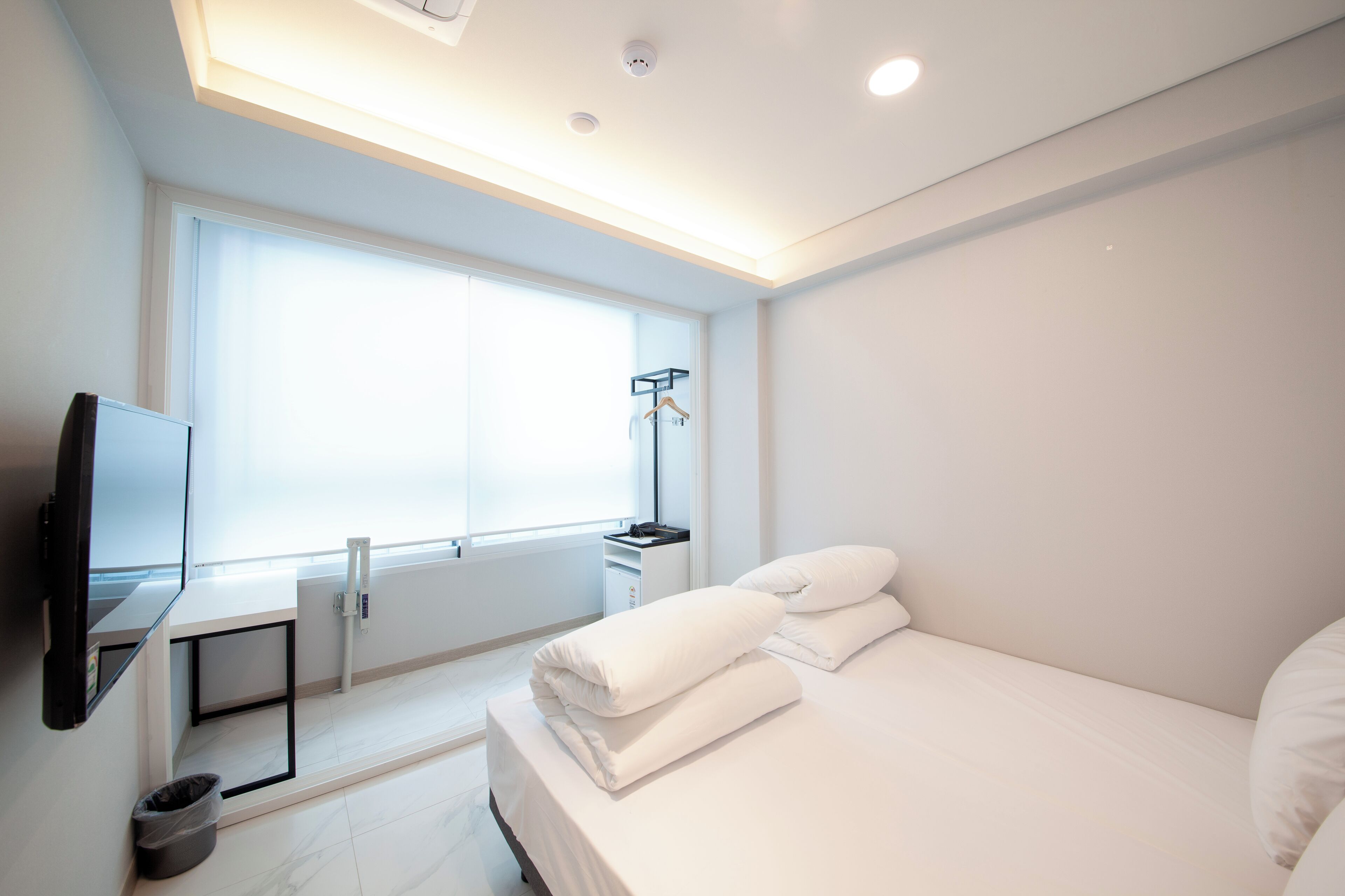 Une chambre d’hôtel moderne équipée d’un lit, d’une télévision, d’un bureau et d’une fenêtre.