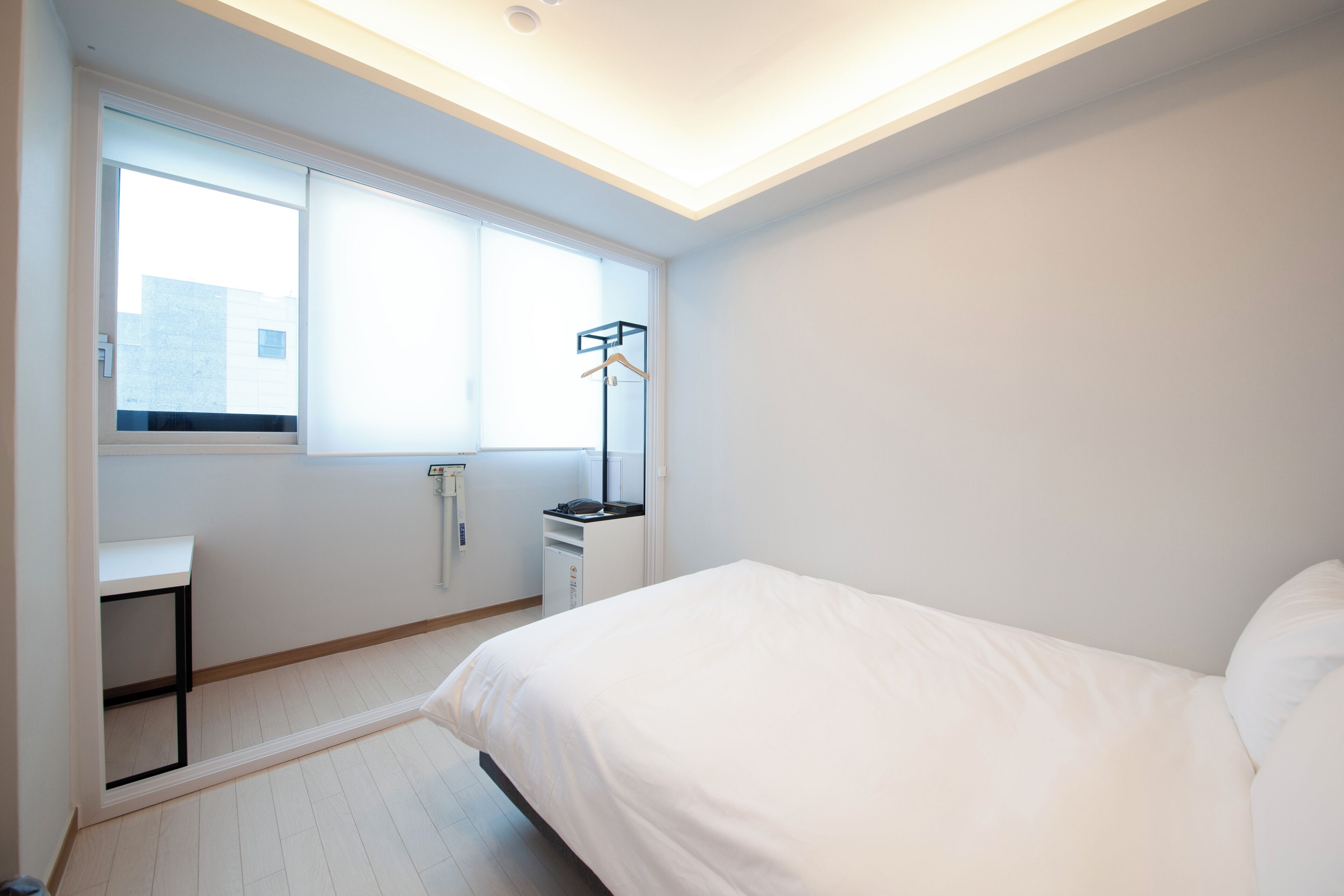Un dormitorio con cama, escritorio, silla, ventana y radiador.