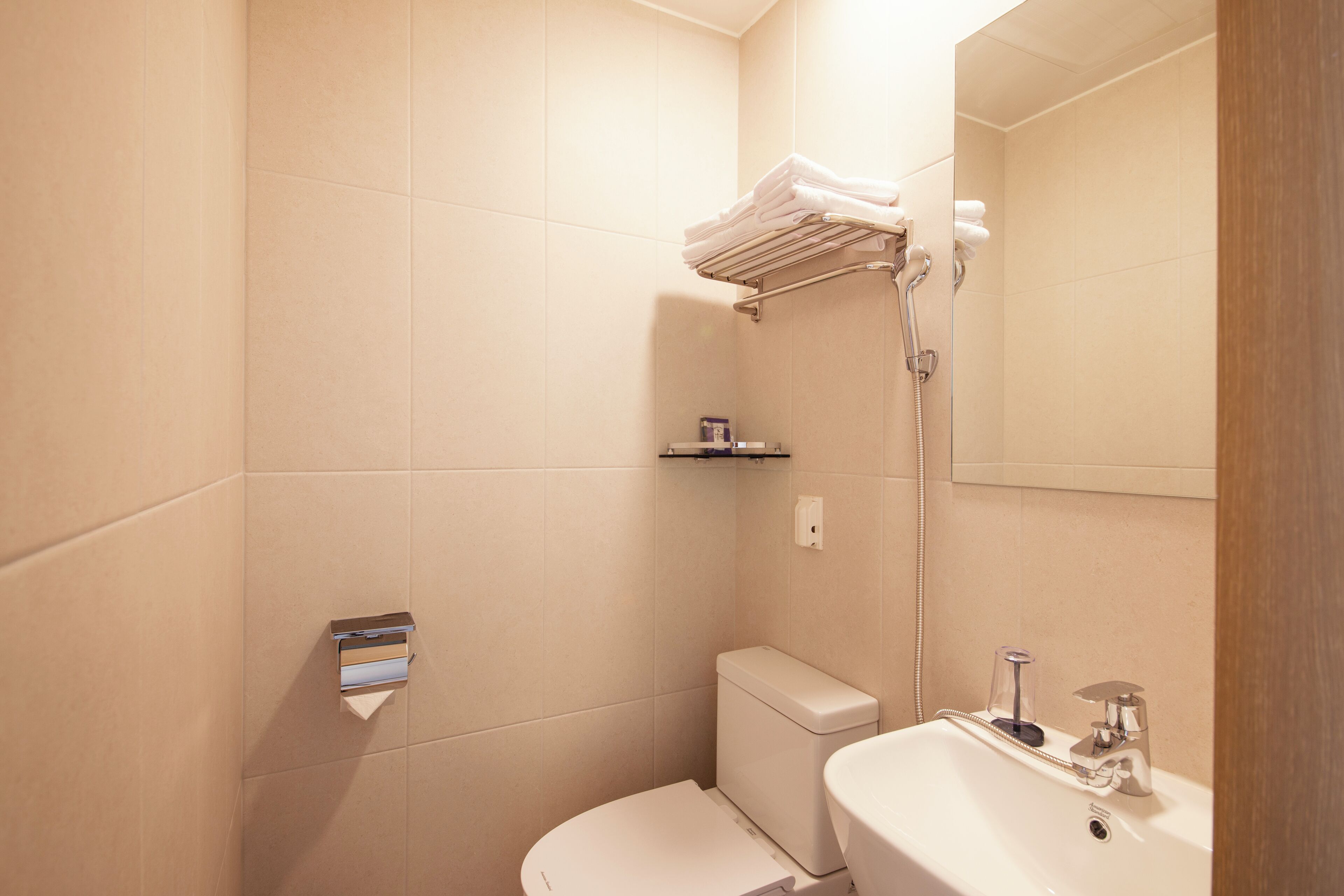 A bathroom with a toilet, sink, towel rack, and shower.