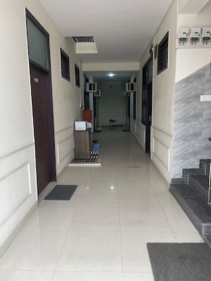Un pasillo con mostrador de recepción, unidades de aire acondicionado, una escalera y una puerta.