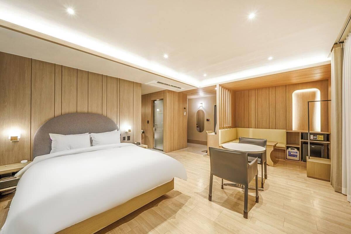 Una habitación de hotel moderna con una cama grande, una zona de comedor y un baño separado.