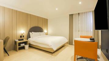 A hotel room with a bed, bedside table, chair, TV, and curtains.