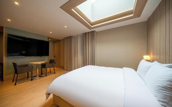 A modern hotel room with a skylight, a bed, a TV, and a small table with chairs. - H Avenue Dongseong-ro Daegu Station (Daegu)
