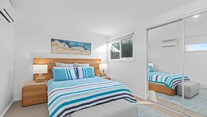 Ein Schlafzimmer mit Bett, Nachttischen, einem Spiegel und einem Fenster.