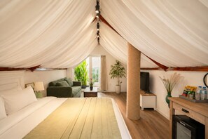 A bedroom with a large bed, a green sofa, a TV, and a window with plants. - Amana Boutique Hotel - Tran Quoc Thao (Ho Chi Minh City)