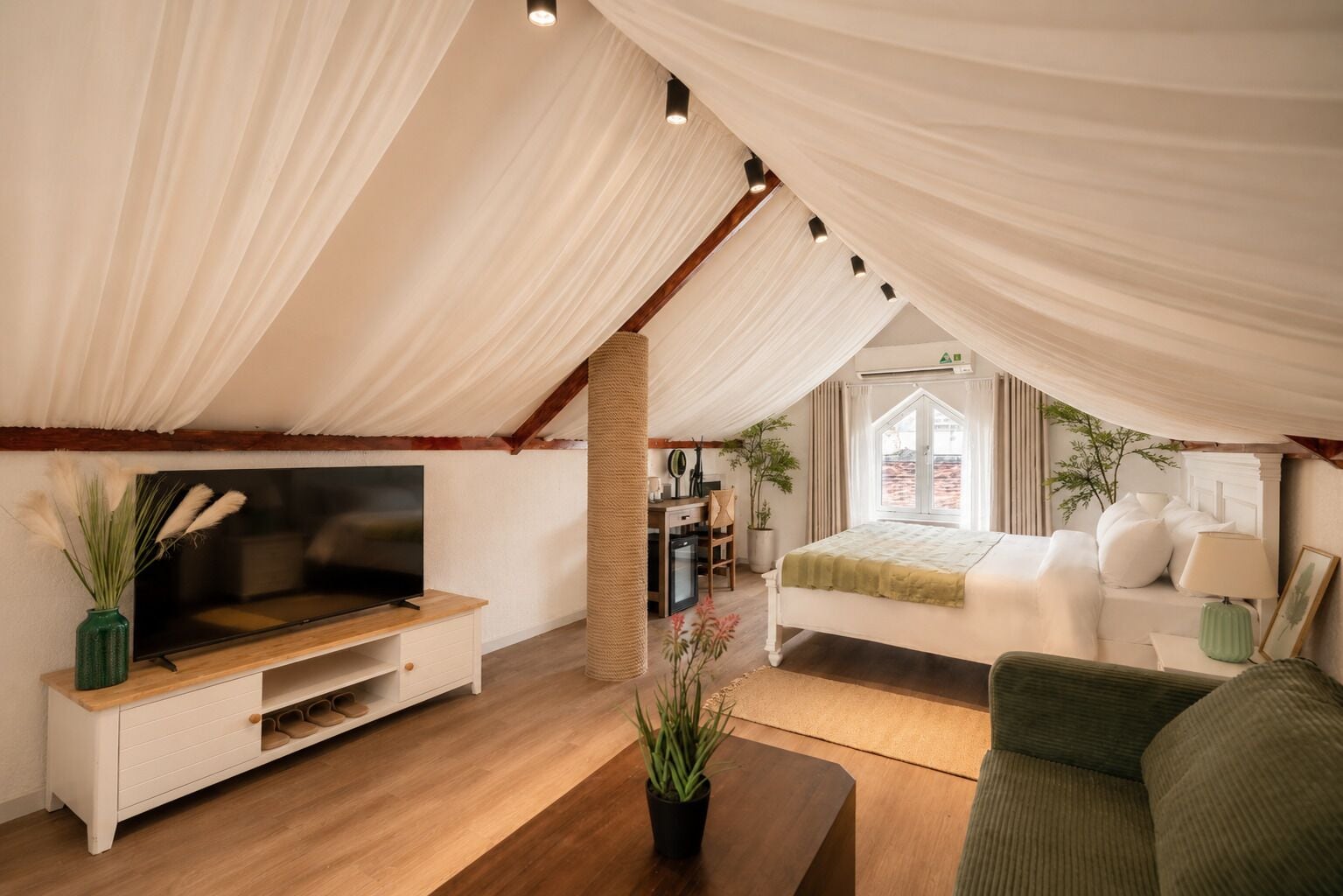 A cozy, well-lit tent-style room with a bed, a television, and a seating area.