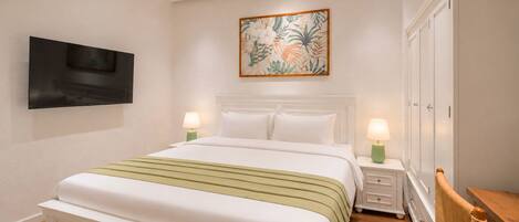Una habitación de hotel con una cama, mesitas de noche con lámparas, un televisor montado en la pared y un armario.