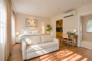 A bedroom with a bed, a sofa, a desk, and a kitchen area. - Amana Boutique Hotel - Tran Quoc Thao (Ho Chi Minh City)
