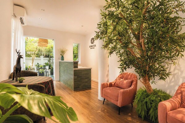 A modern interior with a reception desk, a large tree, and a seating area. - Amana Boutique Hotel - Tran Quoc Thao (Ho Chi Minh City)