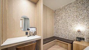 A bathroom with a wooden vanity, a mirror, a hairdryer, a bench, and a stone wall. - Daegu Dongdaegu Station H Avenue Dongdaegu Station Branch (Daegu)
