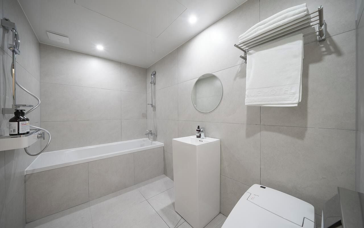 A modern bathroom with a bathtub, a sink, a mirror, and a towel rack.