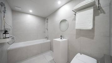 A modern bathroom with a bathtub, a sink, a mirror, and a towel rack.
