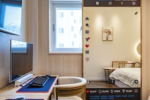 A hotel room with a desk, computer, chair, bed, bedside table, and a window. - Instar Hotel (Suwon)