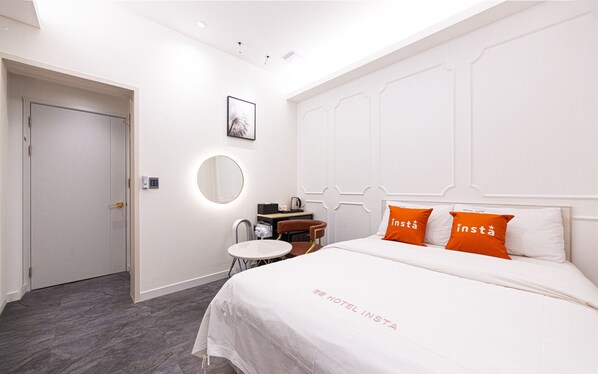 A hotel room with a bed, a bedside table, a chair, a desk, a mirror, and a door. - Instar Hotel (Suwon)
