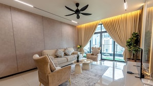 Uma sala de estar moderna com sofá, poltronas, mesa de centro, ventilador de teto e uma janela grande com cortinas.