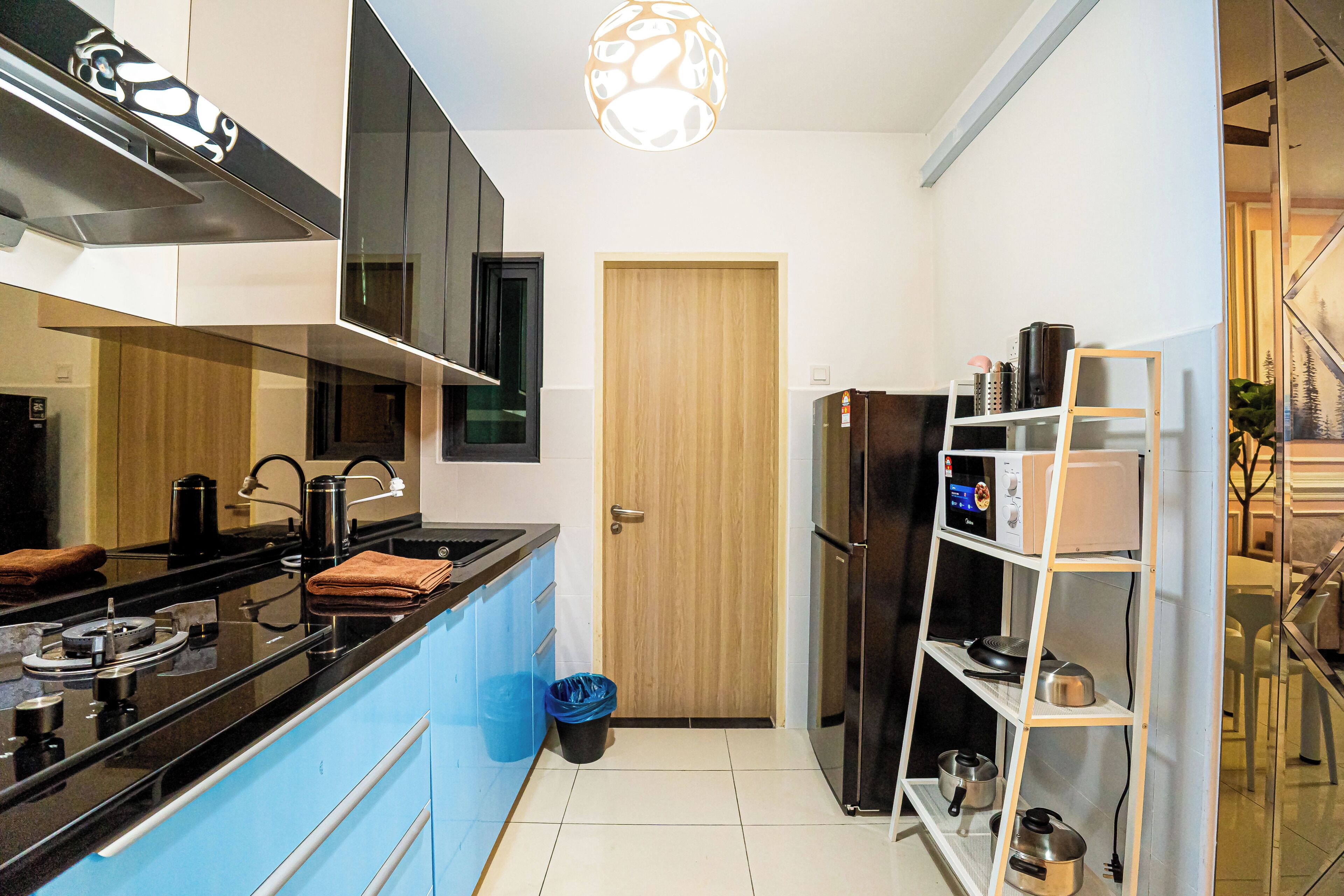 Una cocina moderna con encimera negra, electrodomésticos de acero inoxidable, un armario azul y una puerta de madera.