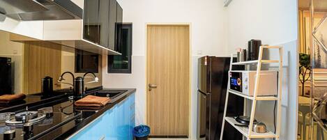 Una cocina moderna con encimera negra, electrodomésticos de acero inoxidable, un armario azul y una puerta de madera.