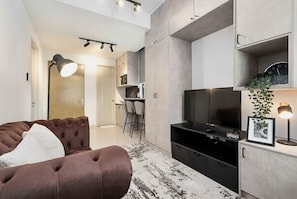 A modern living room with a brown sofa, a flat-screen TV, and a minimalist design.