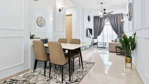 Uma sala de jantar moderna com mesa, cadeiras, um sofá e uma planta.