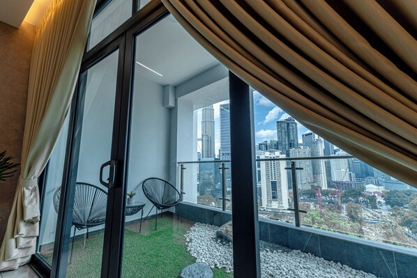 A balcony with a city view, a glass door, and two chairs.