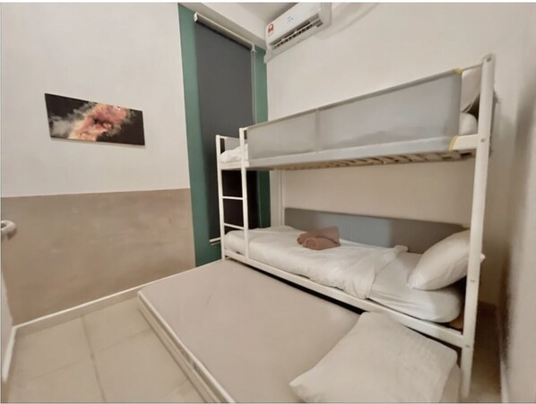 Un lit superposé avec une échelle, un oreiller et un climatiseur fixé au mur.