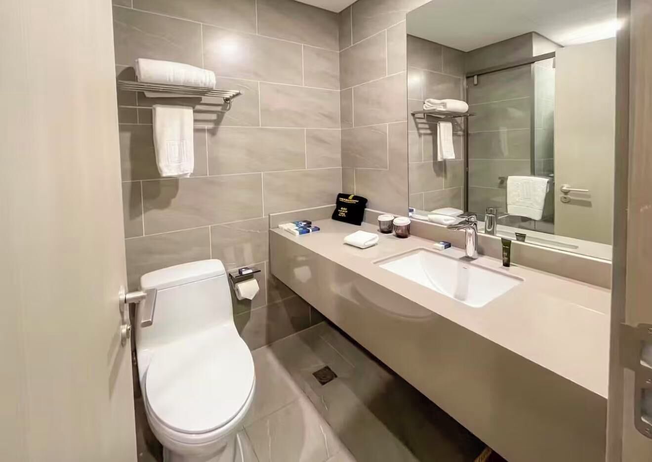 Un baño moderno con inodoro, lavamanos y espejo.